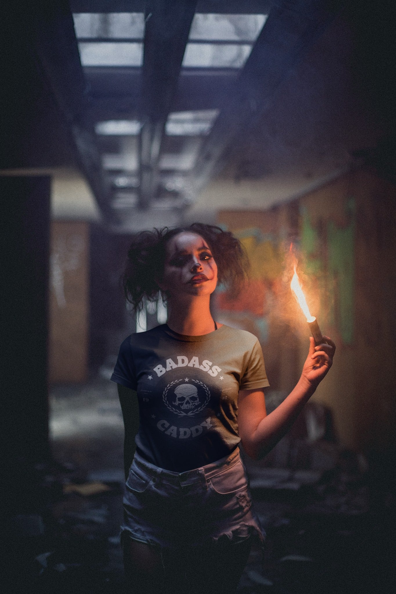 Person holding a lit candle in a dark, dilapidated room with graffiti on the walls.